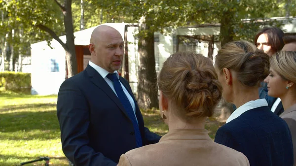 Man in suit talk to his collegues in courtyard. — Stock Photo, Image