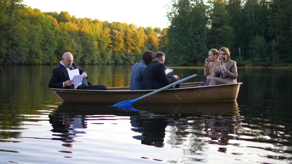 Takım elbiseli insanlar gün batımında bir teknede çalışıyorlar.