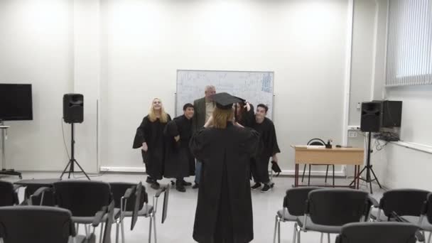 Studenter kastar doktorshattar i luften för foto. — Stockvideo
