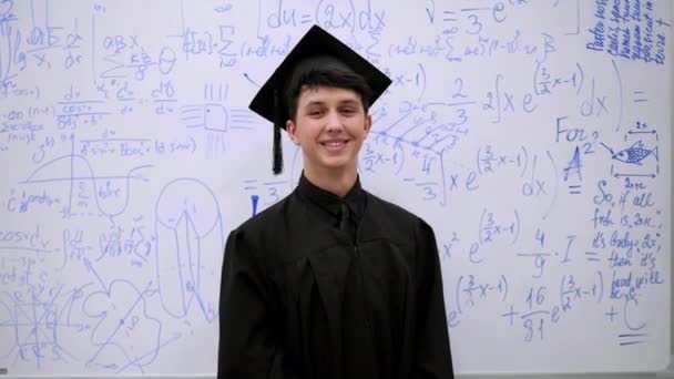 Joven graduado se pone en contra de la junta y sonrisa . — Vídeo de stock
