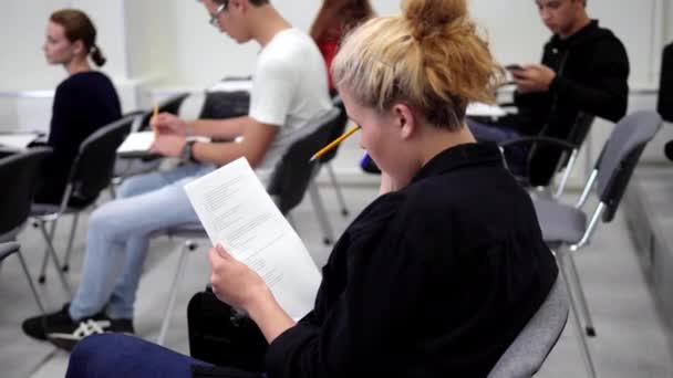 在大学里，拿着纸的女孩坐在教室里. — 图库视频影像