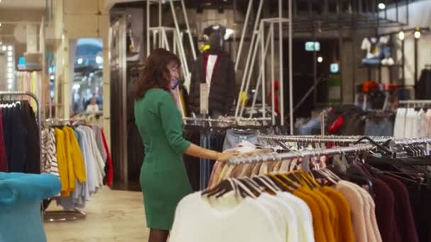 Mujer en vestido elige la ropa y habla por teléfono — Vídeo de stock