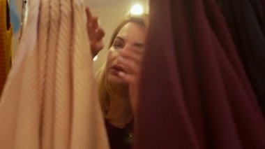 Kız askı yığınından süveter seçiyor.