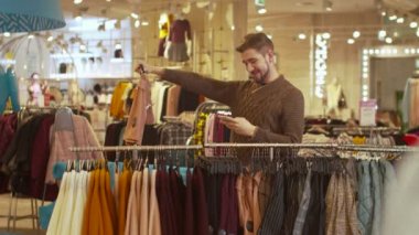 Yakışıklı adam giyim mağazasında fotoğraf çekiyor.