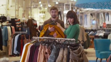 Genç kadın bir askıdan tek tek giysilerini çıkarıyor.