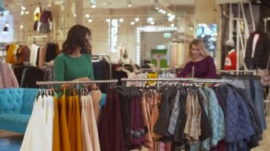 İki kız askıdan elbiselerini çıkarıyor.