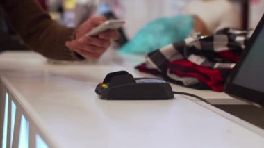 Adam satın almak için telefon yardımıyla ödeme yapıyor.