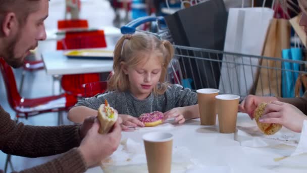 Menina come um donut em um shopping, câmera lenta — Vídeo de Stock