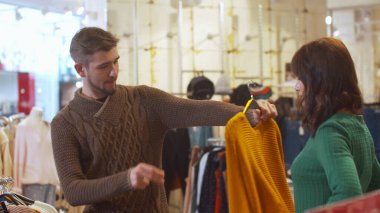 Genç adam karısı için kıyafet seçiyor.