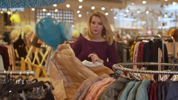 Девушка быстро снимает одежду с вешалки в магазине — стоковое фото
