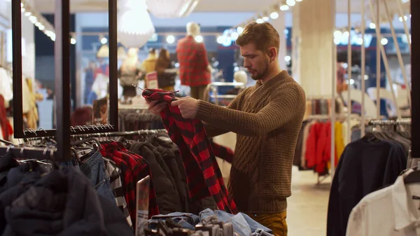 Молодой человек ищет одежду в магазине — стоковое фото