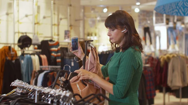 Молодая женщина разговаривает по телефону и показывает шорты и свитер — стоковое фото