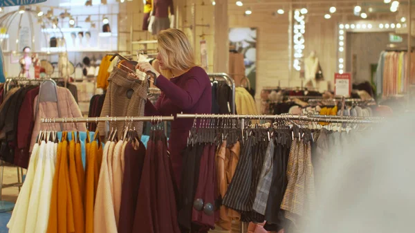 Mujer joven elige pantalones cortos en la tienda — Foto de Stock