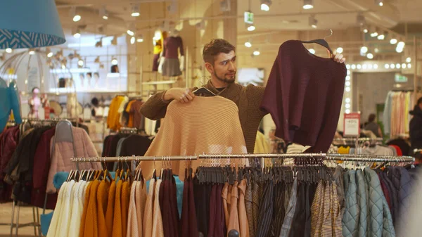Парень ищет некий свитер в магазине — стоковое фото