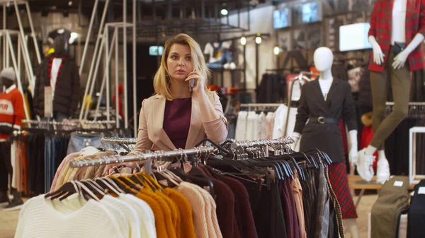 Красивая девушка разговаривает по телефону в магазине одежды — стоковое фото