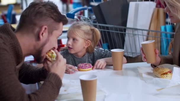 Счастливая семья ест и разговаривает в торговом зале — стоковое видео
