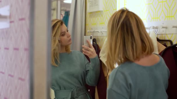 Женщина делает фотографию в зеркале в примерочной — стоковое видео