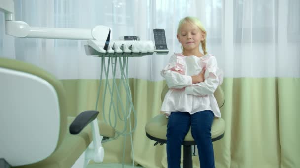 Mała dziewczynka siedzi z ręką w dłoni na krześle dentystycznym — Wideo stockowe
