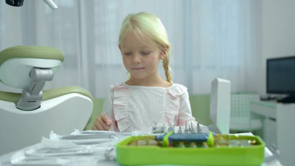 Mała dziewczynka liczy instrumenty na stole. — Wideo stockowe