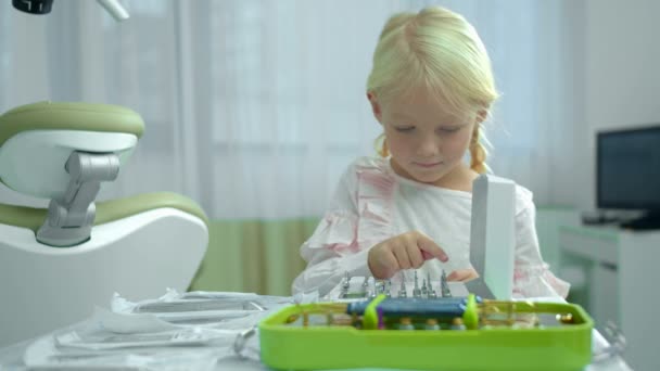 Ładna dziewczyna liczy instrumenty na stole dentystycznym — Wideo stockowe