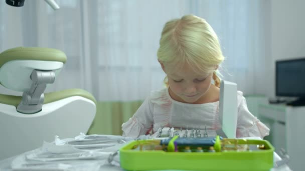 Klein meisje kijkt naar tandheelkundige instrumenten in kast — Stockvideo