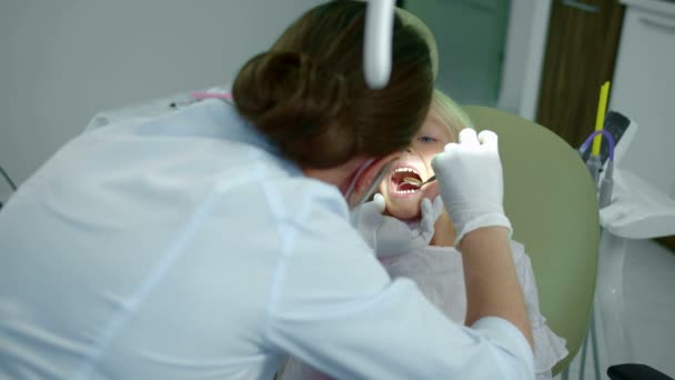 Dentista está olhando para meninas dentes com pouco espelho . — Vídeo de Stock