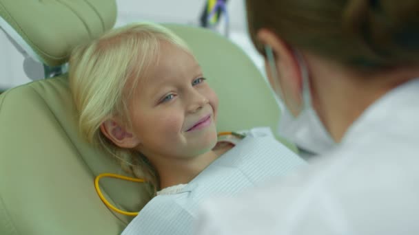 Menina olha com um sorriso para o médico que lhe diz algo . — Vídeo de Stock