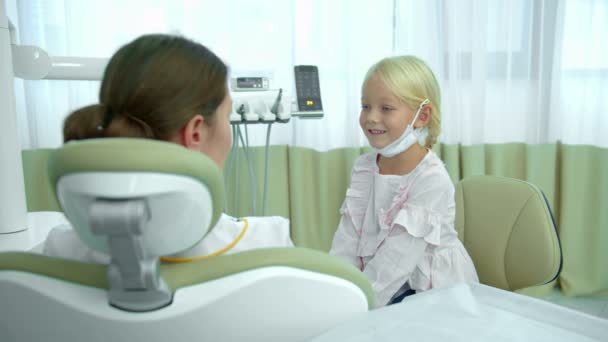Κορίτσι κάθεται στην καρέκλα οδοντίατροι και μιλάει με τον οδοντίατρο — Αρχείο Βίντεο