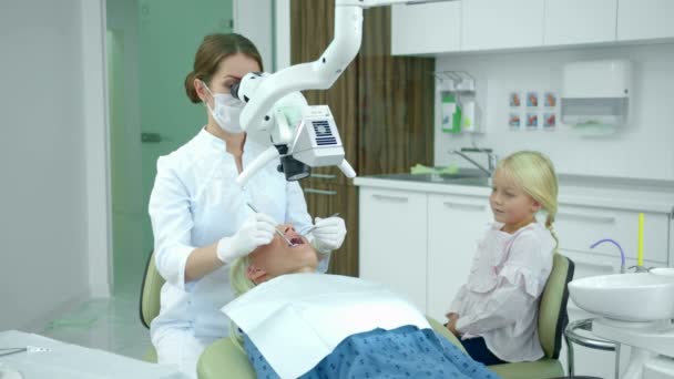 치과 의사는 치과 기구를 사용하여 여자들의 치아를 바라본다 — 비디오