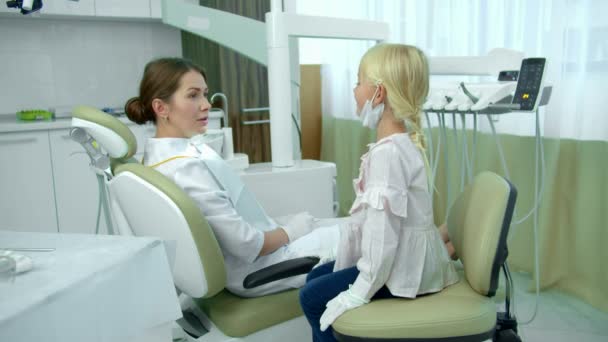 歯医者はキャビネットの女の子と話します — ストック動画