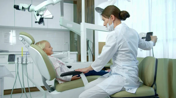 Dentista move cadeira para trás, menina senta-se . — Fotografia de Stock