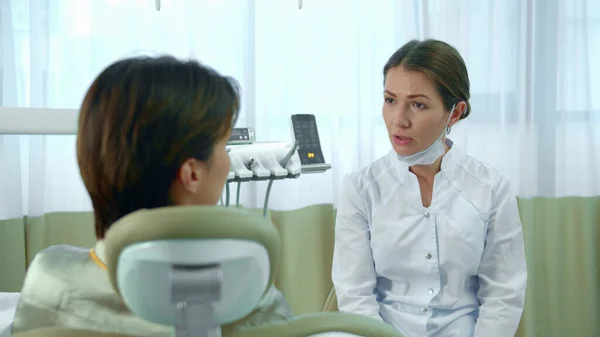 Doutor tira uma máscara enquanto conversa com um paciente — Fotografia de Stock