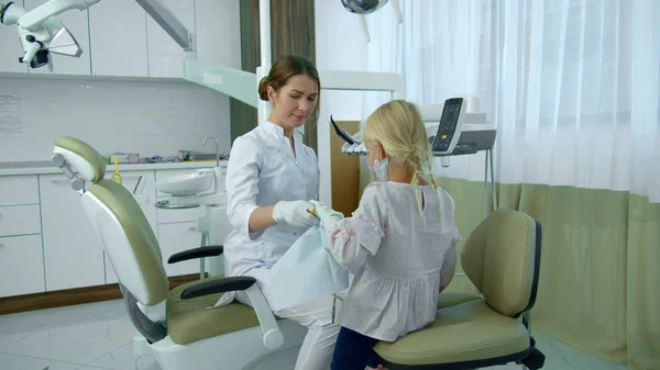 Meisje verwijdert een luier van de tandarts en ze schudt handen — Stockfoto