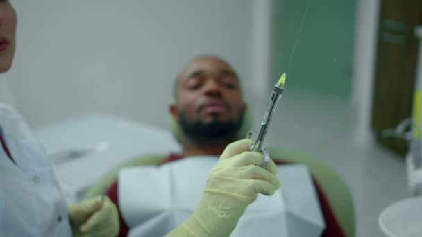Dentista hace una inyección a un hombre joven — Vídeo de stock