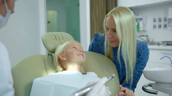 Mutter hält Tochter an der Hand, Zahnarzt erklärt etwas — Stockfoto