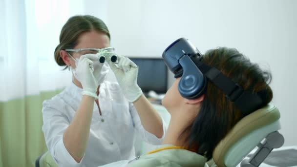 Zubař reguluje speciální brýle před prací — Stock video