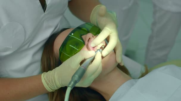 Девушка пришла в клинику и зубной врач чистит ей зубы — стоковое видео