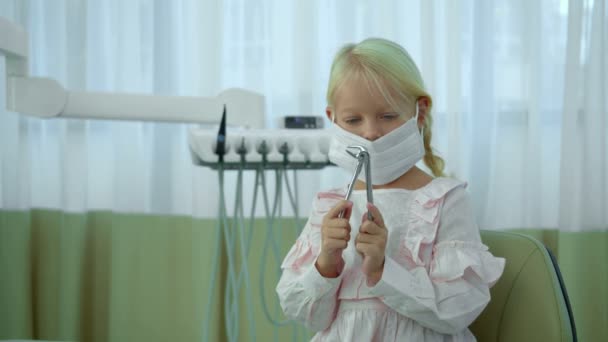 Маленька дівчинка в раптовій масці грає з сосками — стокове відео