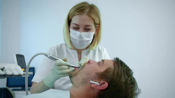 Dentista escova os dentes com um equipamento elétrico — Fotografia de Stock
