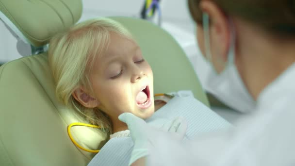 Стоматолог наклав світло на рот дівчат і дивиться на зуби . — стокове відео