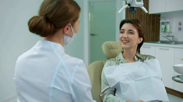 Kız dişçiyle konuşurken bir şey gösteriyor.