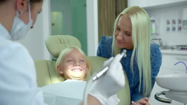 Zahnarzt zeigt eine medizinische Bohrmaschine, ein Mädchen lacht — Stockvideo