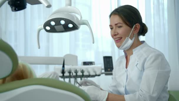 Tandläkaren riktar en lampa mot flickornas mun och tittar på hennes tänder. — Stockvideo