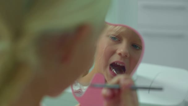 Kleines Mädchen blickt im Spiegel auf ihre Zähne. — Stockvideo