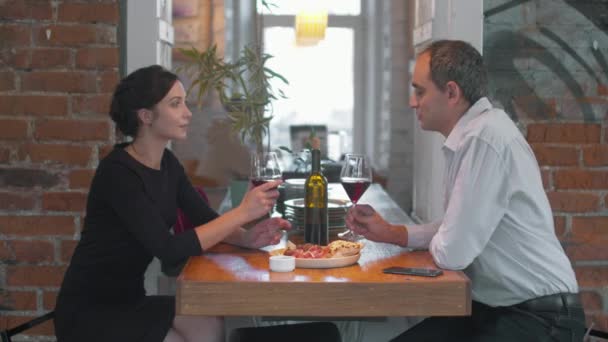 Romantyczna kolacja, facet mówi toast i stukają szklankami — Wideo stockowe
