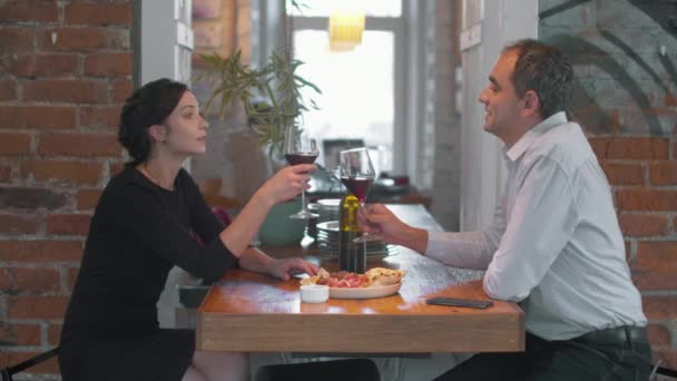 Pareja en la cena romántica, ellos tintinean copas de vino — Vídeo de stock
