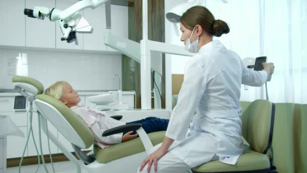 Dentista move cadeira para trás, menina senta-se . — Vídeo de Stock