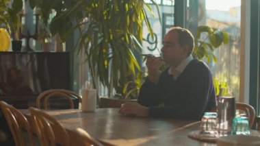 Adam kafede oturuyor ve bir sesli mesaj kaydediyor.