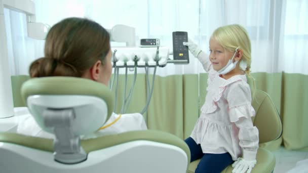 Fille se déplace chaise en arrière, où le dentiste est assis — Video