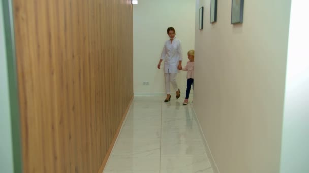 Doktor spaceruje z dziewczyną wzdłuż korytarza i rozmawia — Wideo stockowe